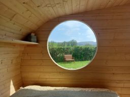 Cosy wooden cabin interior with a bed, table, and warm lighting.