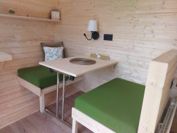 Interior of a wooden cabin with round windows and a minimalist design.