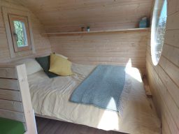 Wooden octagonal wood fired hot tub with slatted seating and a metal heater.